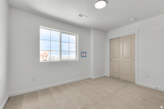 7797 West Alta Springs Way Magna, UT 84044 - Photo 21 of 21 Unfurnished bedroom featuring light carpet, a closet, and a textured ceiling