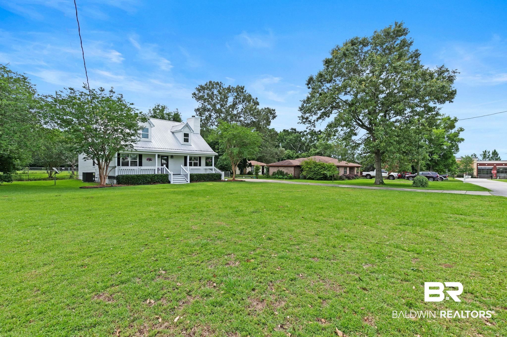 22810 High Ridge Road Fairhope, AL 36532 - Photo 12 of 78 White two-story home featuring a covered front porch with white railing, a metal roof, and dormer windows