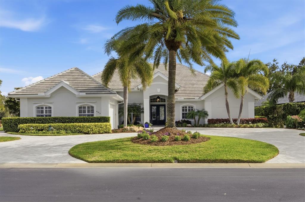 a view of a white house with a yard and palm trees
