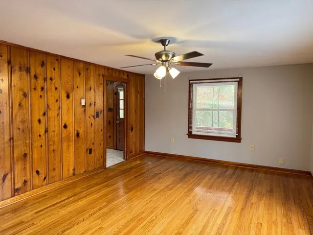 a view of an empty room with window and wooden floor