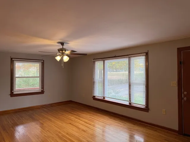 a view of an empty room with a window and wooden floor