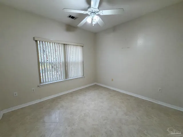 an empty room with a window and a ceiling fan