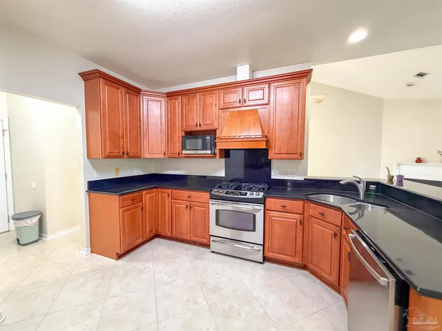 a kitchen with stainless steel appliances granite countertop a sink a stove and a refrigerator