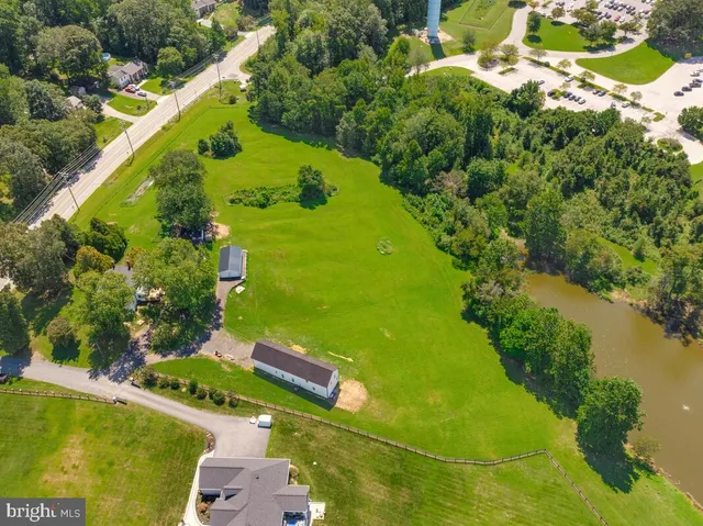 an aerial view of a residential houses with outdoor space and trees all around
