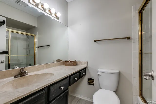 a bathroom with a granite countertop toilet sink and mirror