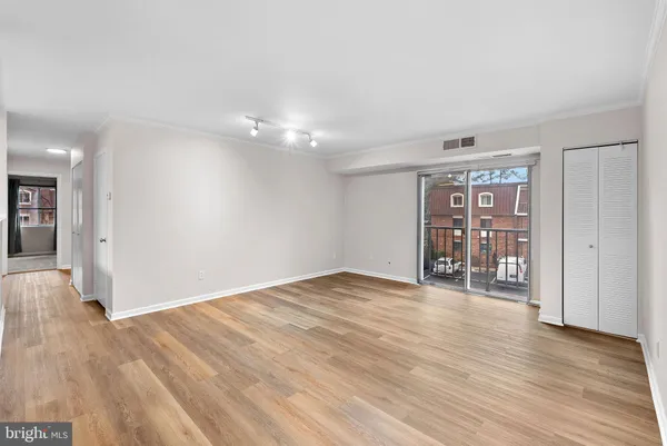 a view of an empty room with window and wooden floor