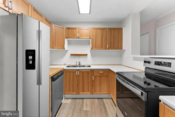 a kitchen with stainless steel appliances a refrigerator a sink and wooden cabinets