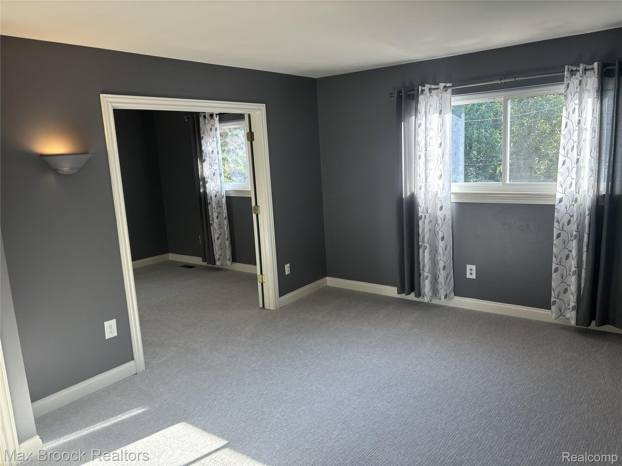 126 Manor Way Rochester, MI 48309 - Photo 19 of 31 Neutral gray wall paint, light gray carpet, multiple windows, white trim, and a wall-mounted sconce