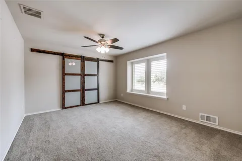 an empty room with windows and fan