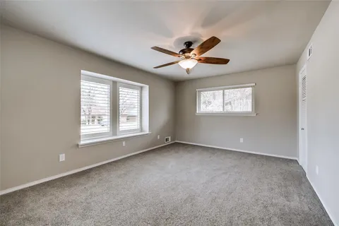 an empty room with a window and a fan