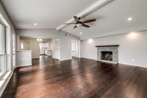 an empty room with wooden floor fireplace and windows