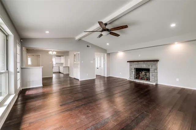 an empty room with wooden floor fireplace and windows