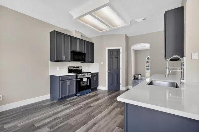 a kitchen with a sink and a stove top oven with wooden floor