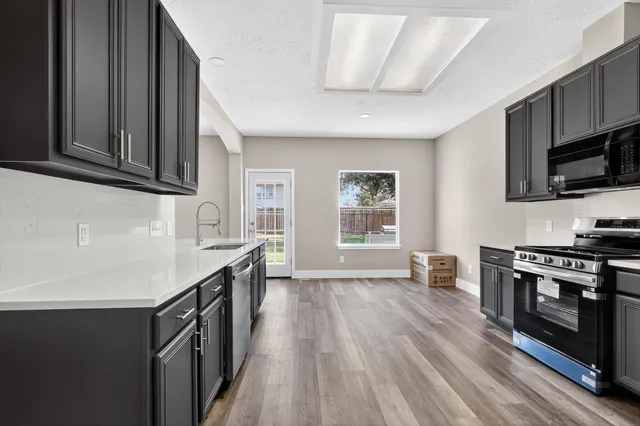 a kitchen with granite countertop a stove top oven a sink dishwasher and wooden cabinets with wooden floor