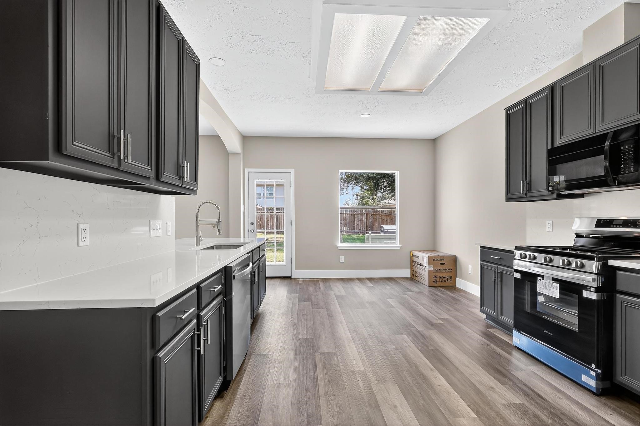 20926 Trellis Lane Houston, TX 77073 - Photo 15 of 24 a kitchen with granite countertop a stove top oven a sink dishwasher and wooden cabinets with wooden floor