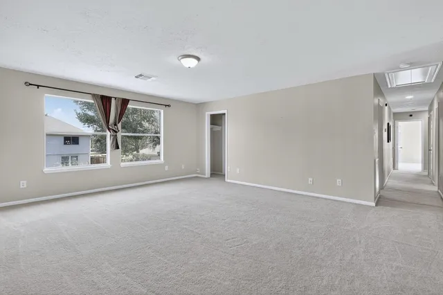 a view of a big room with windows and chandelier fan
