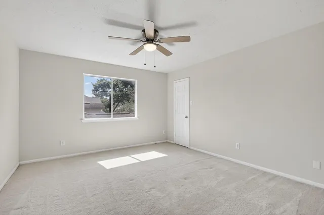 an empty room with a window and a fan
