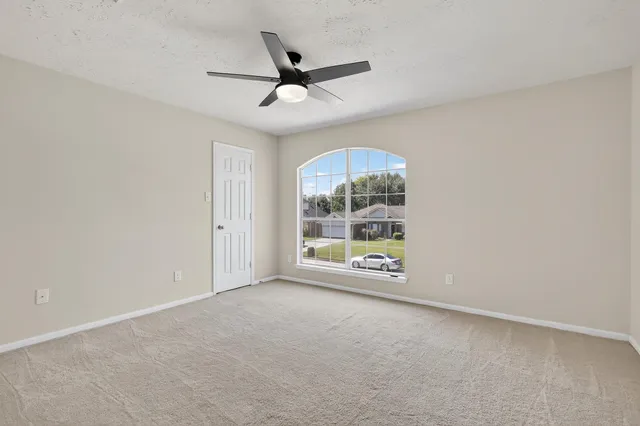an empty room with a ceiling fan and window
