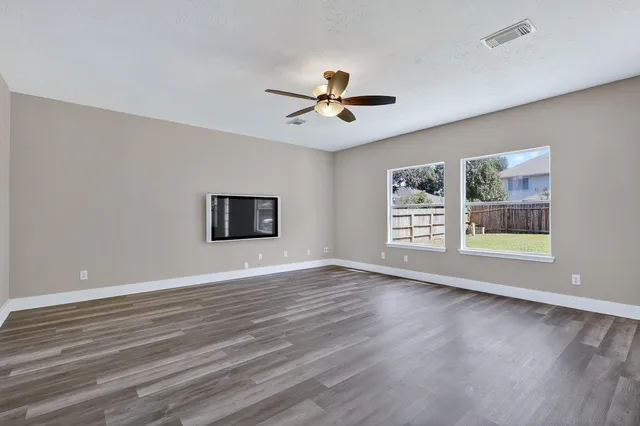 a view of an empty room with a window and wooden floor