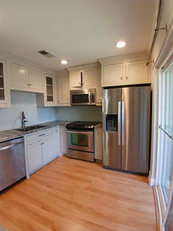 a kitchen with granite countertop a refrigerator and a stove top oven