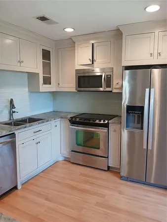 a kitchen with cabinets stainless steel appliances and wooden floor