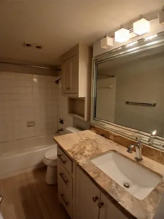 a bathroom with a granite countertop sink a toilet and bathtub