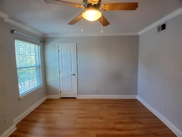 an empty room with wooden floor fan and windows