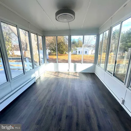 a view of an empty room with wooden floor and a large window with an outdoor view