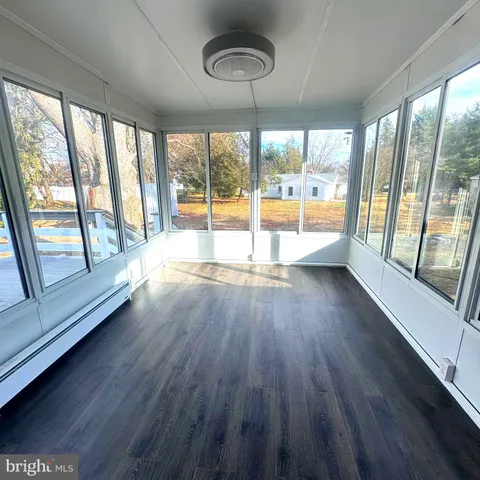 a view of an empty room with wooden floor and a large window with an outdoor view