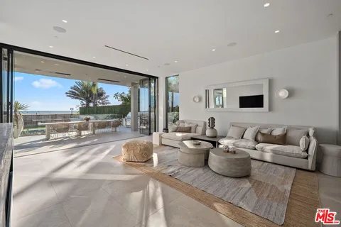 a living room with lots of white furniture and a large window