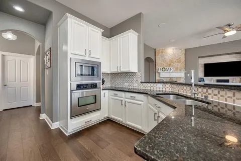 a kitchen with granite countertop a stove and a microwave