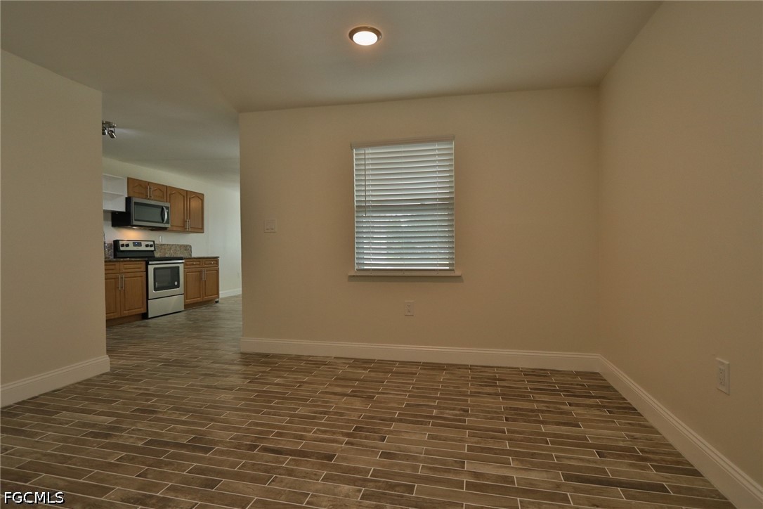 11 California Road Lehigh Acres, FL 33936 - Photo 17 of 19 a view of empty room with kitchen view and wooden floor
