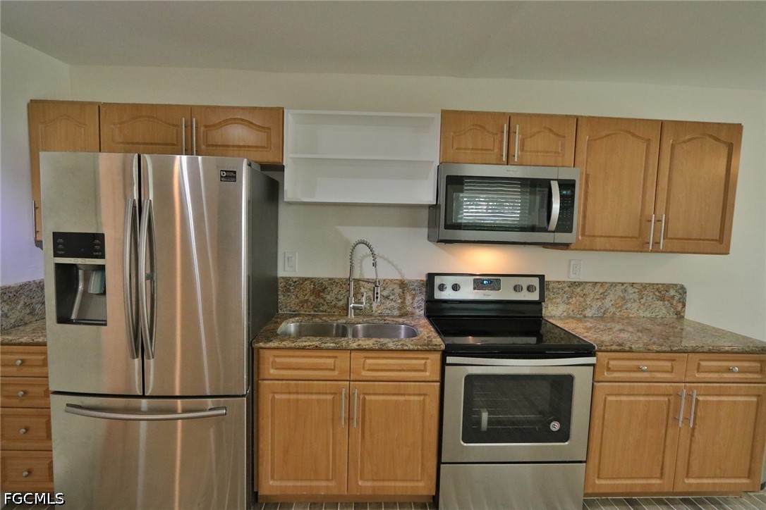 11 California Road Lehigh Acres, FL 33936 - Photo 18 of 19 a kitchen with stainless steel appliances granite countertop a refrigerator microwave and stove top oven