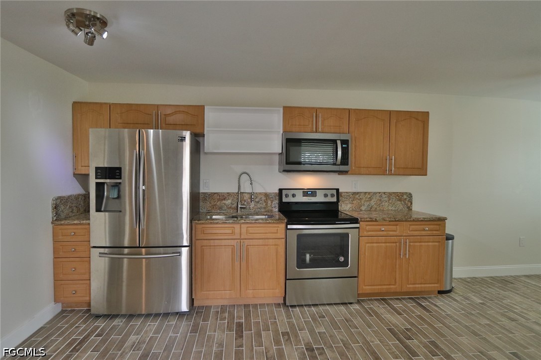 11 California Road Lehigh Acres, FL 33936 - Photo 4 of 19 a kitchen with a refrigerator stove and wooden cabinets