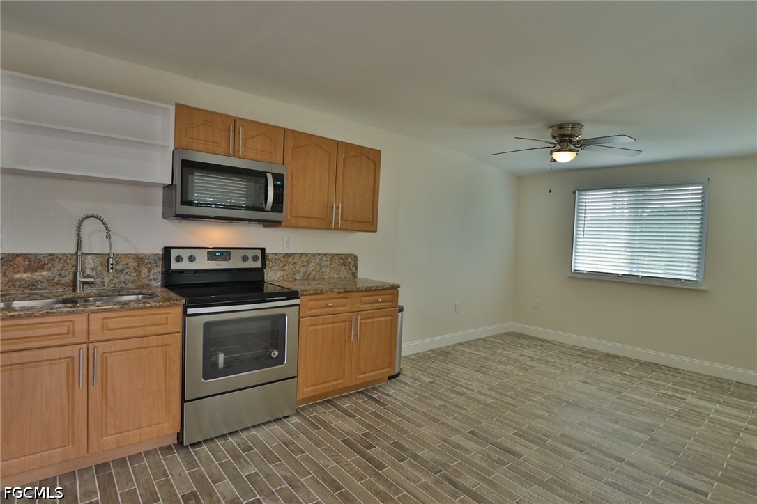 11 California Road Lehigh Acres, FL 33936 - Photo 5 of 19 a kitchen with stainless steel appliances granite countertop a sink a stove a microwave and cabinets