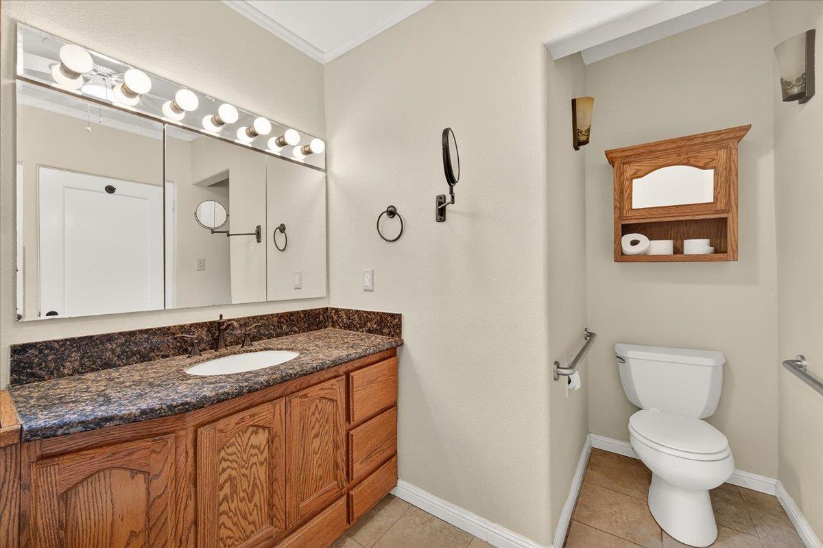 311 South K Street Madera, CA 93637 - Photo 8 of 46 a bathroom with a granite countertop sink a toilet and a mirror