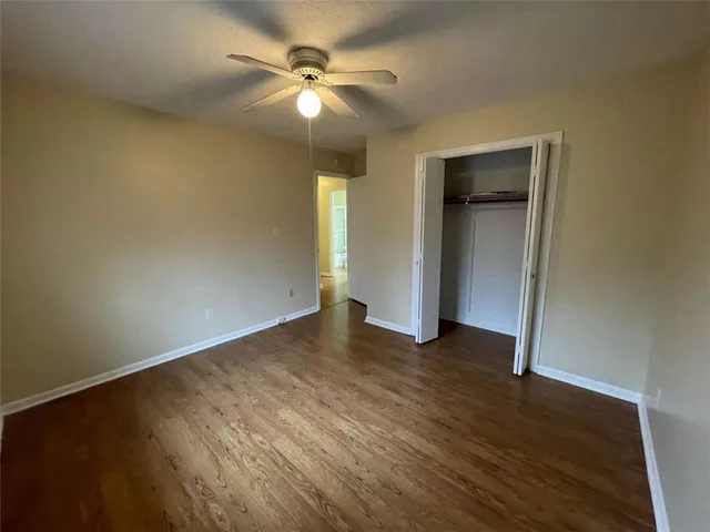an empty room with wooden floor and fan