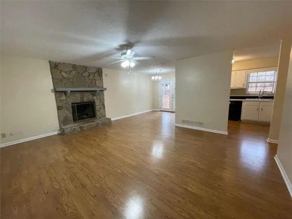 an empty room with wooden floor fireplace and chandelier