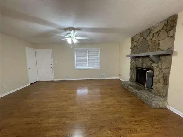 an empty room with windows fireplace and a kitchen view