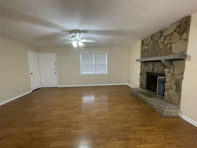 an empty room with windows fireplace and a kitchen view
