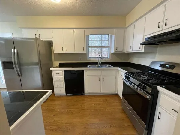 a kitchen with stainless steel appliances granite countertop a stove a sink and a refrigerator