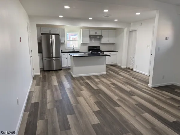 a kitchen with stainless steel appliances kitchen island granite countertop a refrigerator and a sink