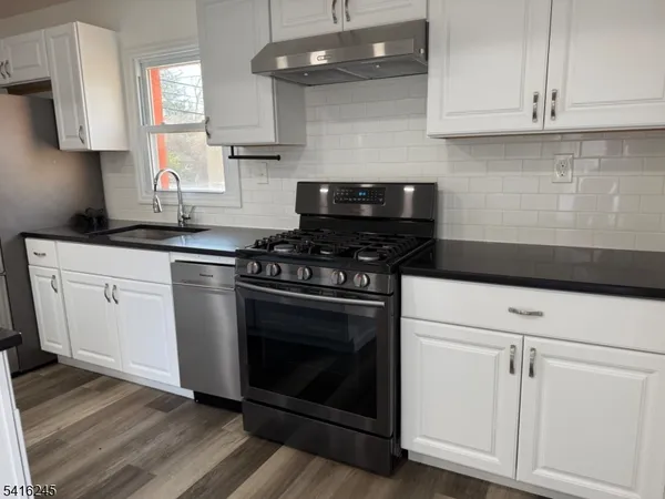 a kitchen with white cabinets and appliances