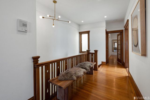 a view of a hallway with wooden floor and stairs