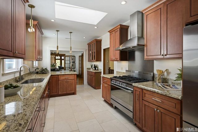 a kitchen with stainless steel appliances granite countertop a stove top oven a sink dishwasher a refrigerator and cabinets with wooden floor
