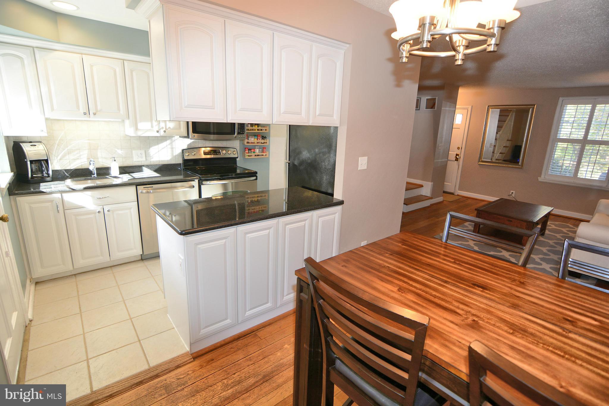 a kitchen with stainless steel appliances a white stove top oven a sink dishwasher and white cabinets with wooden floor