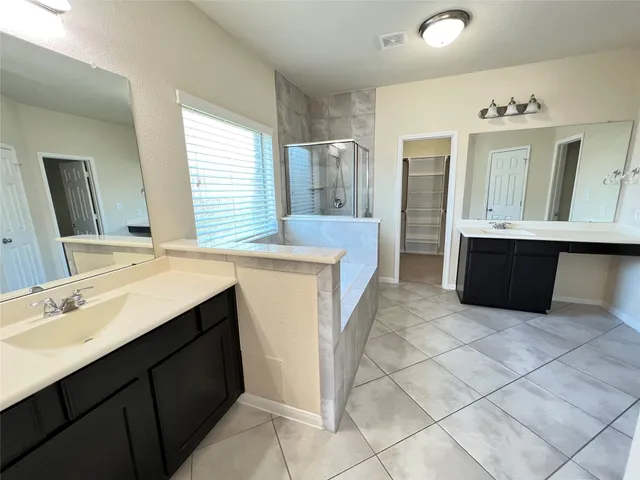 a spacious bathroom with a tub sink and mirror