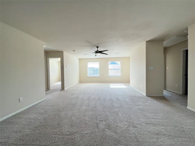 an empty room with windows and fan