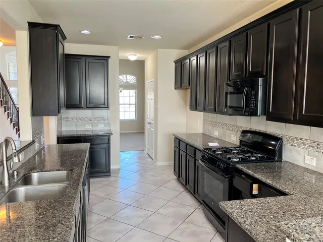 a kitchen with granite countertop stove top oven microwave and cabinets