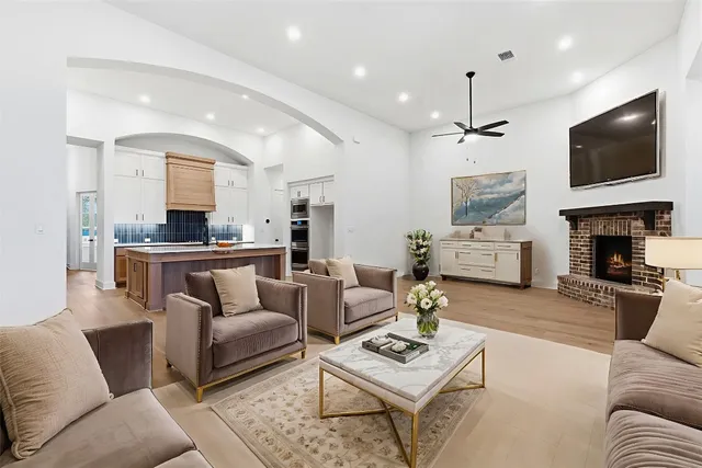 a living room with furniture a fireplace a flat screen tv and kitchen view